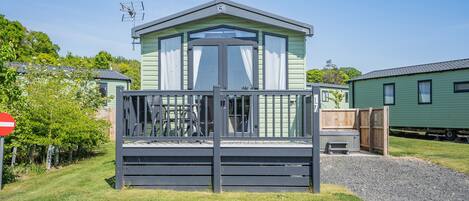 A mobile home with a fenced front yard, a clear sky, and a 'no entry' sign.