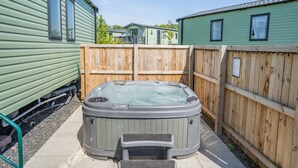 A hot tub in a fenced backyard with wooden fencing and a green building in the background. - Coldstream Retreat - 3 Bedroom (Pet Friendly) (Coldstream)