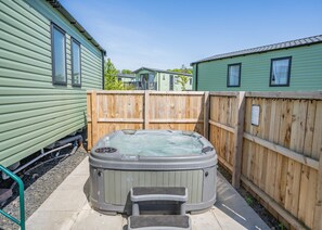 A hot tub in a fenced backyard with wooden fencing and a green building in the background. - Coldstream Retreat - 3 Bedroom (Pet Friendly) (Coldstream)