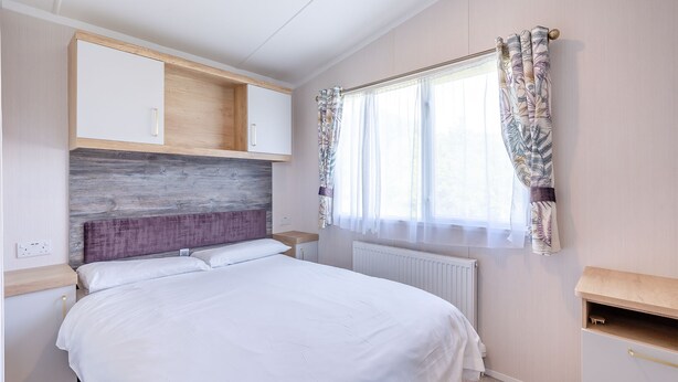 A bedroom with a bed, a wooden headboard, a window with curtains, and built-in cabinets. - Coldstream Retreat - 3 Bedroom (Pet Friendly) (Coldstream)