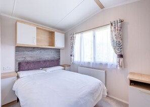 A bedroom with a bed, a wooden headboard, a window with curtains, and built-in cabinets. - Coldstream Retreat - 3 Bedroom (Pet Friendly) (Coldstream)