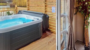 Un jacuzzi en una terraza de madera con vista a un lago y árboles.