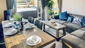 Un comedor con una mesa de madera dispuesta para cuatro personas, un sofá y vistas al exterior.