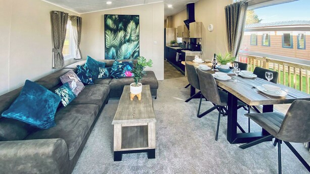 A modern living room with a sofa, coffee table, and dining area with chairs and a table set for two.