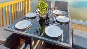 A dining table set for four with a bottle of wine, glasses, and a potted plant.