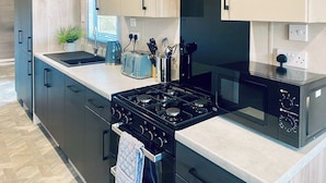 A modern kitchen with a gas stove, microwave, and a toaster.