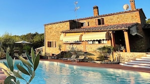 Eine Steinvilla mit Swimmingpool, Satellitenschüsseln und blauem Himmel.