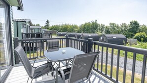A deck with a table and chairs, a railing, and a view of the surrounding area.
