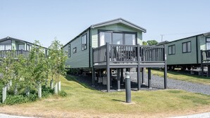 A row of green mobile homes with a central unit featuring a balcony.