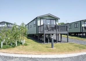 A row of green mobile homes with a central unit featuring a balcony. - Tweed Retreat - 2 Bedroom (Pet Friendly) (Coldstream)