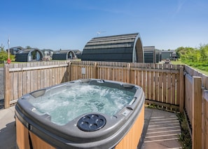A hot tub in a backyard with a wooden fence, a picnic table, and a small building in the background. - Cheviot Retreat - 2 Bedroom (Pet Friendly) (Coldstream)