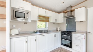 A modern kitchen with white cabinets, a microwave, a stove, and a window. - Cheviot Retreat - 2 Bedroom (Pet Friendly) (Coldstream)