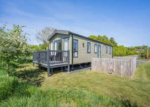 A single-story mobile home with a balcony, a fenced yard, and a clear sky. - Cheviot Retreat - 2 Bedroom (Pet Friendly) (Coldstream)
