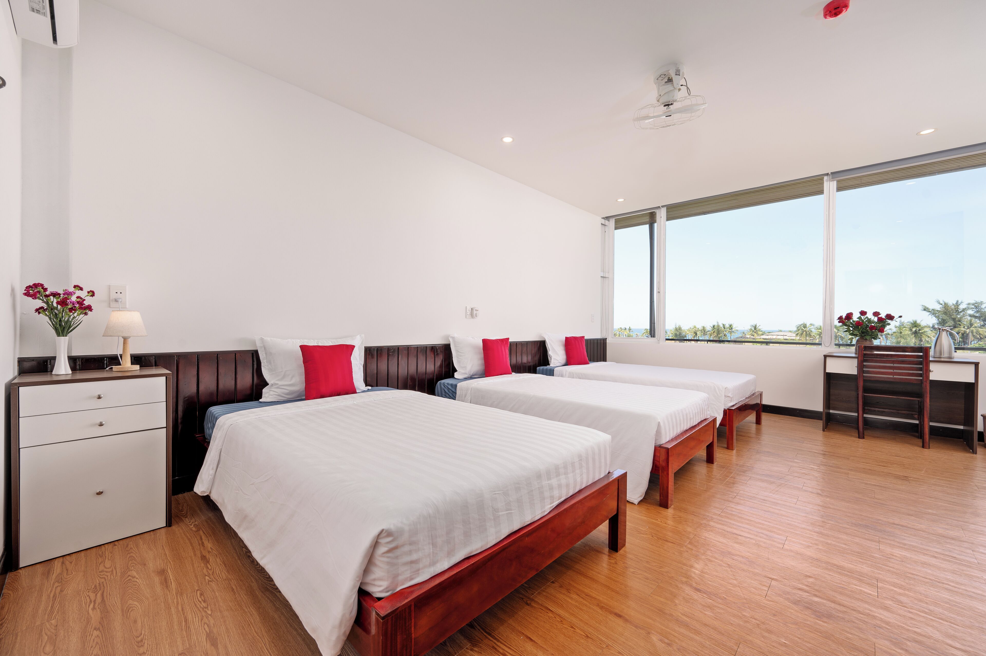 Une chambre d’hôtel avec trois lits, un bureau et une chaise.