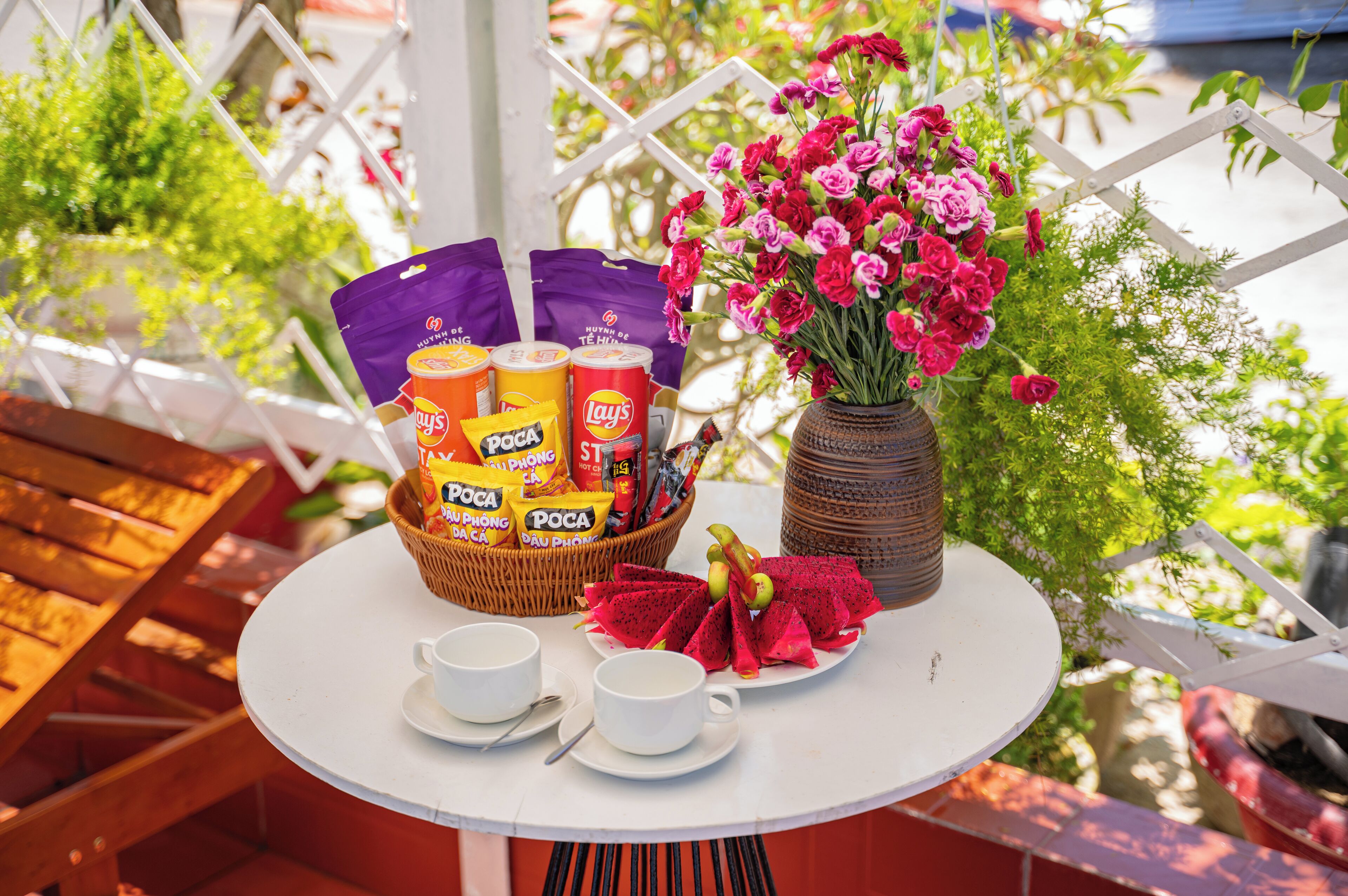 A table with snacks, a vase of flowers, and a plate of dragon fruit.