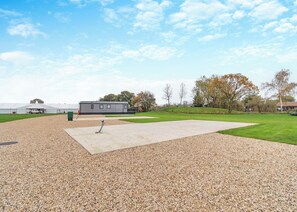 Un espace extérieur recouvert de gravier, avec une terrasse en béton, un camion blanc et un bâtiment en arrière-plan.