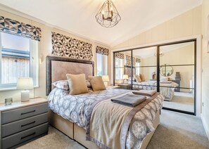 A bedroom with a large bed, bedside tables, a mirror, and a sliding door closet.