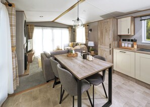 Eine moderne Küche mit einem Holztisch, grauen Stühlen und einer Kaffeemaschine.