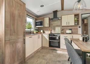 A modern kitchen with wooden cabinets, a stove, microwave, and a dining area with a table and chairs.