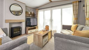 A modern living room with a television, sofa, and a fireplace. - Platinum Caravan (Pet) (Bedale)
