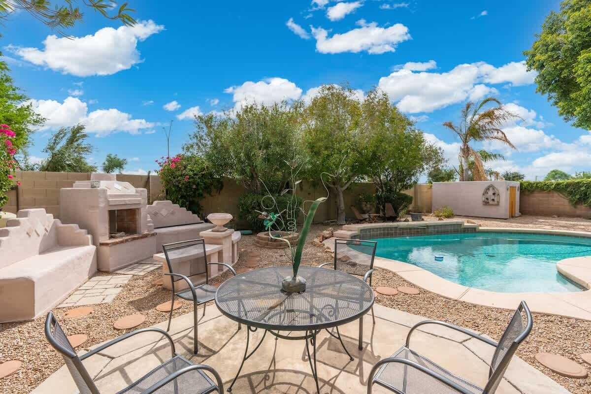 Un jardin avec une piscine, un espace salon extérieur et un foyer.