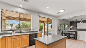 Une cuisine moderne dotée d’un îlot central, de meubles en bois et offrant une vue sur l’extérieur.