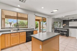 A modern kitchen with a central island, wooden cabinets, and a view to the outside.