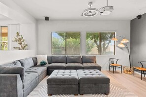 A modern living room with a sectional sofa, ottoman, and a floor lamp.