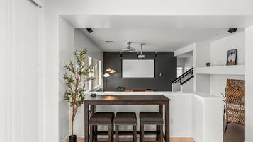 Une cuisine moderne avec un revêtement mural foncé, un plan de travail blanc et trois tabourets.