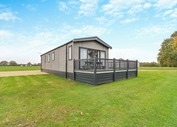 Einbungalow auf Rädern mit einer Terrasse, gelegen auf einer grünen Wiese.