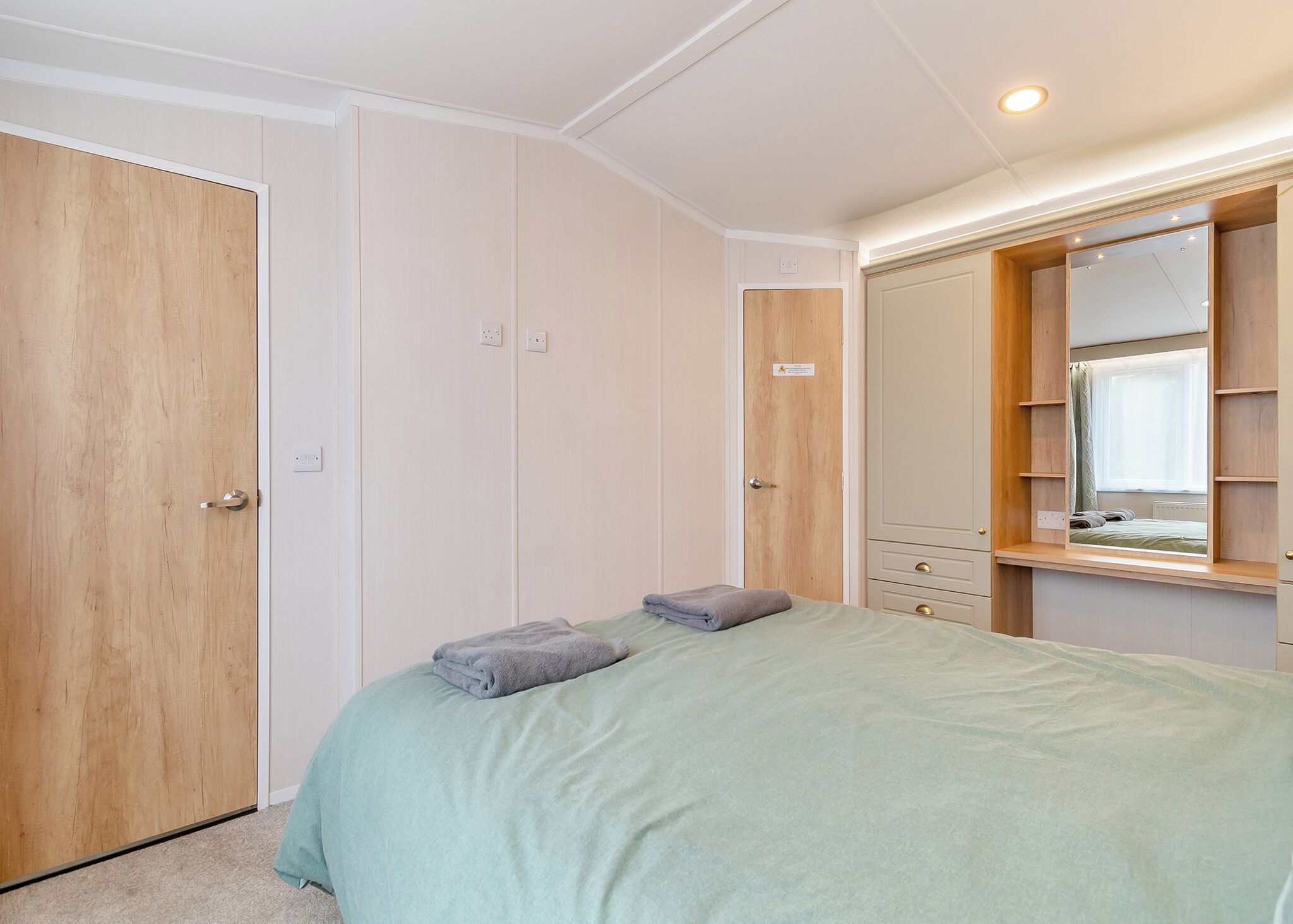 A bedroom with a bed, a wardrobe, and a mirror.