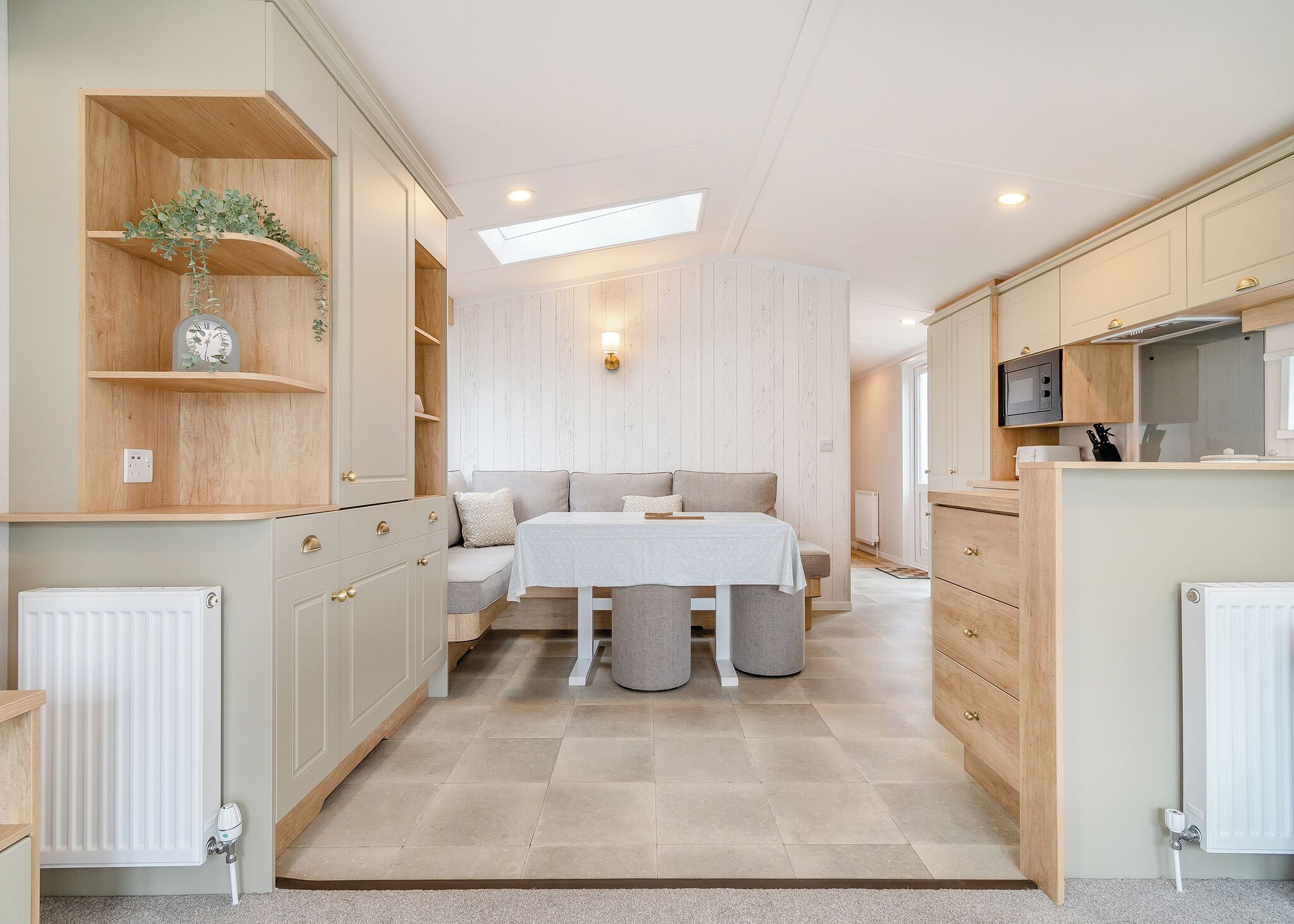 A compact kitchen with a dining area, wooden cabinets, and a skylight.