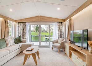 Una sala de estar acogedora con sofá, sillón, mesa de centro, televisor y puerta corrediza de vidrio que da a una terraza.