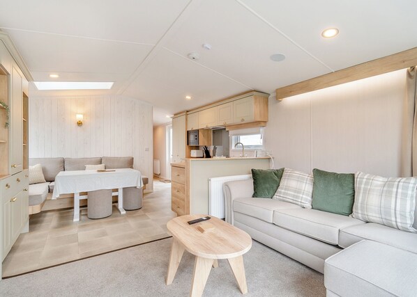 A compact living space with a sofa, a small table, a dining area, and a kitchenette.