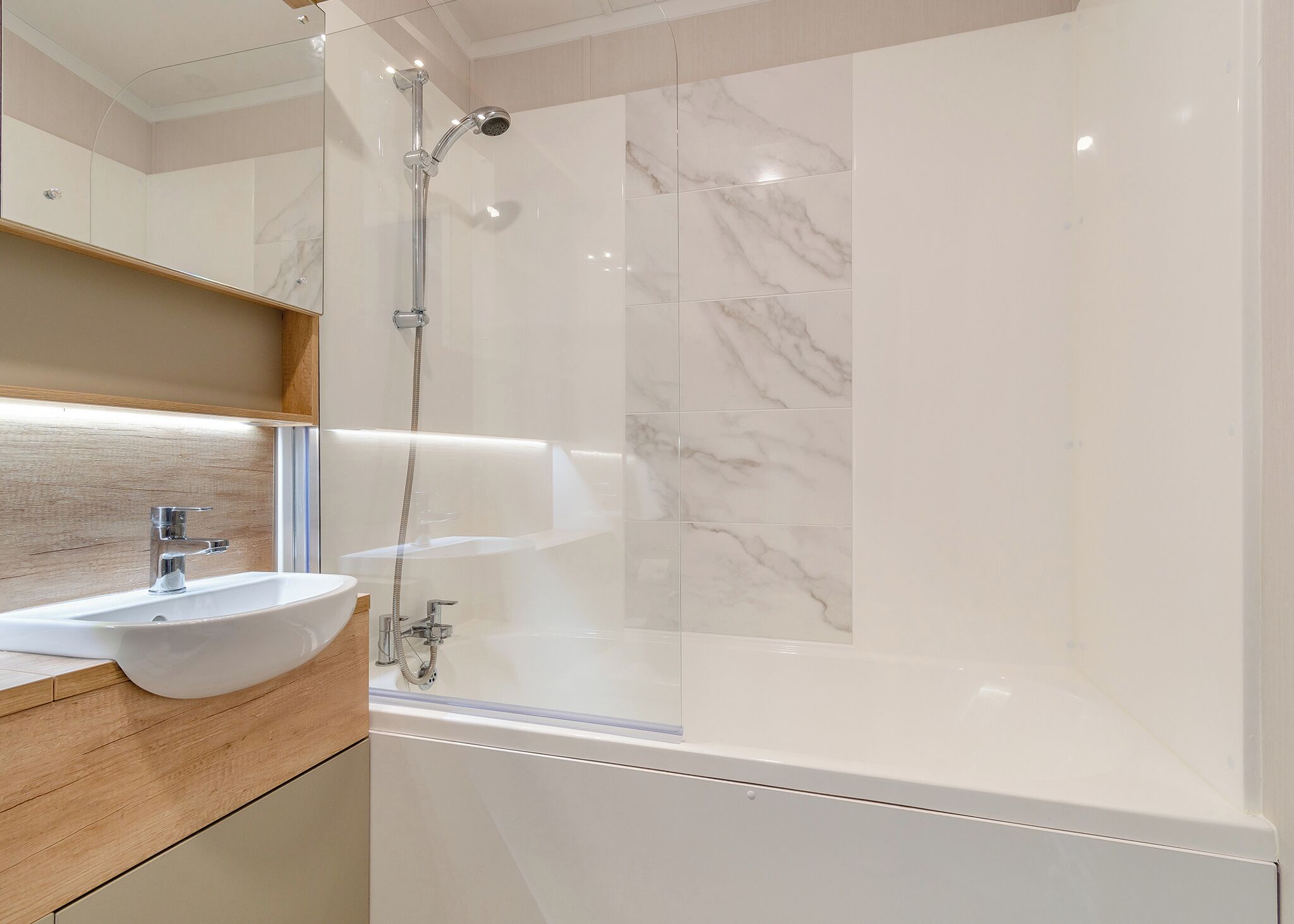 A modern bathroom with a glass-enclosed shower, a white sink, and marble tiles.