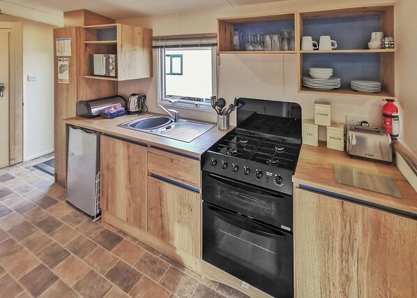 A compact kitchen with a built-in stove, sink, and a small refrigerator.
