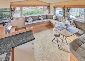Interior de uma RV compacta, com área de cozinha, assentos e mesa de jantar.