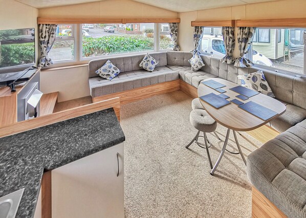 Un intérieur de camping-car compact comprenant un coin cuisine, des sièges et une table à manger.