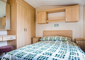 A bedroom with a bed, a desk, a chair, and wooden cabinets.