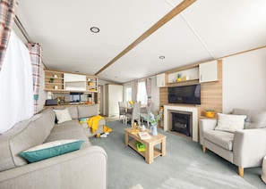 A modern living room with a sofa, armchairs, a coffee table, a fireplace, and a TV. - Platinum 2 Bed Hot Tub (Pet) (Clarach Bay, Nr Aberystwyth)
