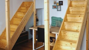 A loft-style room with a wooden staircase, a desk, and a chair.