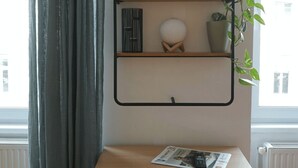 A room with a wooden cabinet, a black metal shelf with decorative items, and a potted plant.