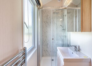 Un baño moderno con ducha vidriada, lavamanos y ventana.