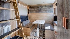 A compact, well-lit interior with a bed, seating area, and a small table. - Aura Chalet (Pet Friendly) (Coldstream)