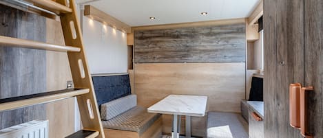 A compact, well-lit interior with a bed, seating area, and a small table.
