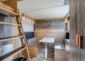 A compact, well-lit interior with a bed, seating area, and a small table.