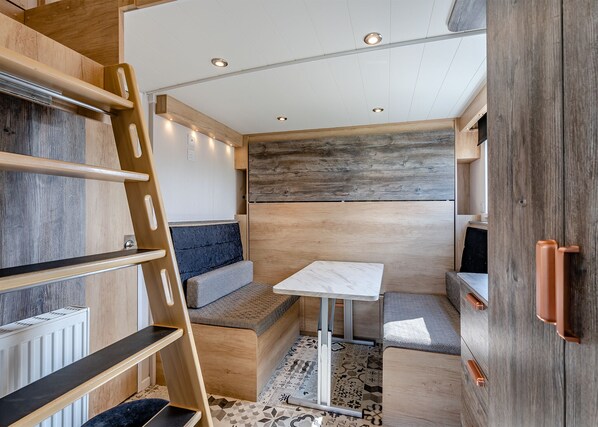 A compact, well-lit interior with a bed, seating area, and a small table. - Aura Chalet (Pet Friendly) (Coldstream)
