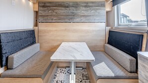 A compact interior with a central table, two cushioned seating areas, and a window providing a view. - Aura Chalet (Pet Friendly) (Coldstream)