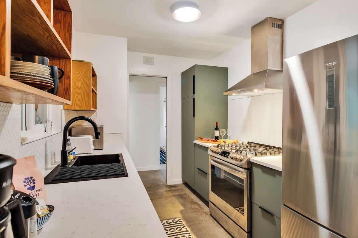 A modern kitchen with a stainless steel refrigerator, a built-in oven, and a coffee machine.