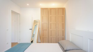 Un dormitorio con una cama, un armario de madera y un espejo apoyado contra la pared.